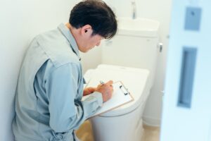 温水洗浄便座の前で書類に記入する作業員