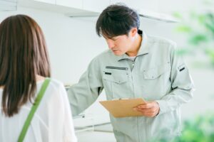 キッチンで住人に説明する作業服の作業員